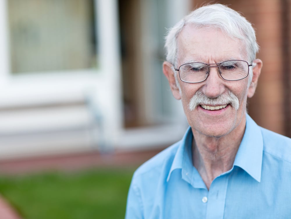 Retired man smiling outside his house